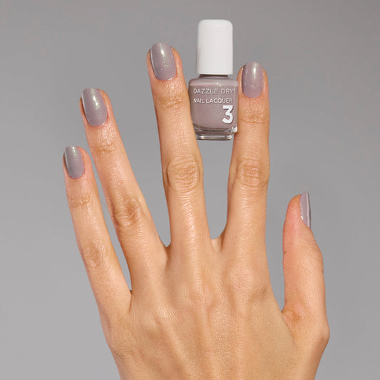 Hand with Let's Glow painted on fingernails holding mini nail polish bottle