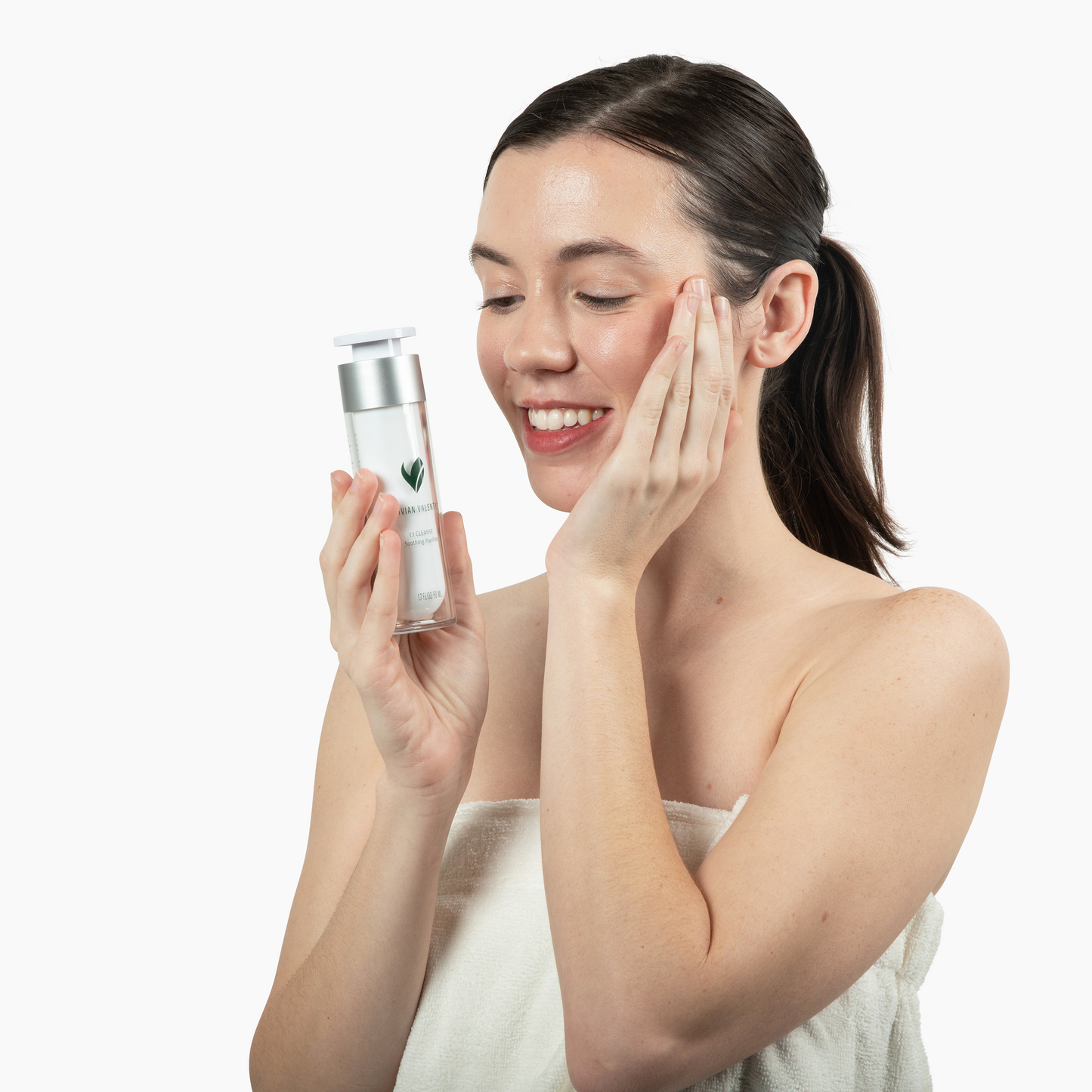 Woman applying skincare product to her face with a white background