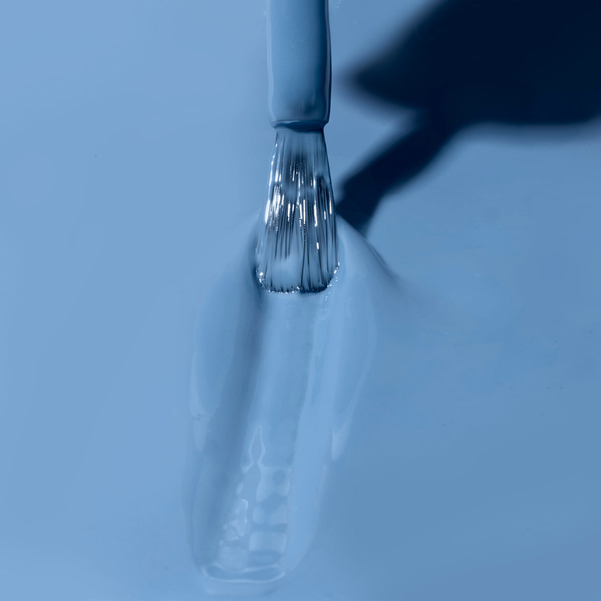 Hand with Varsity Blues painted on nails holding mini lacquer bottle