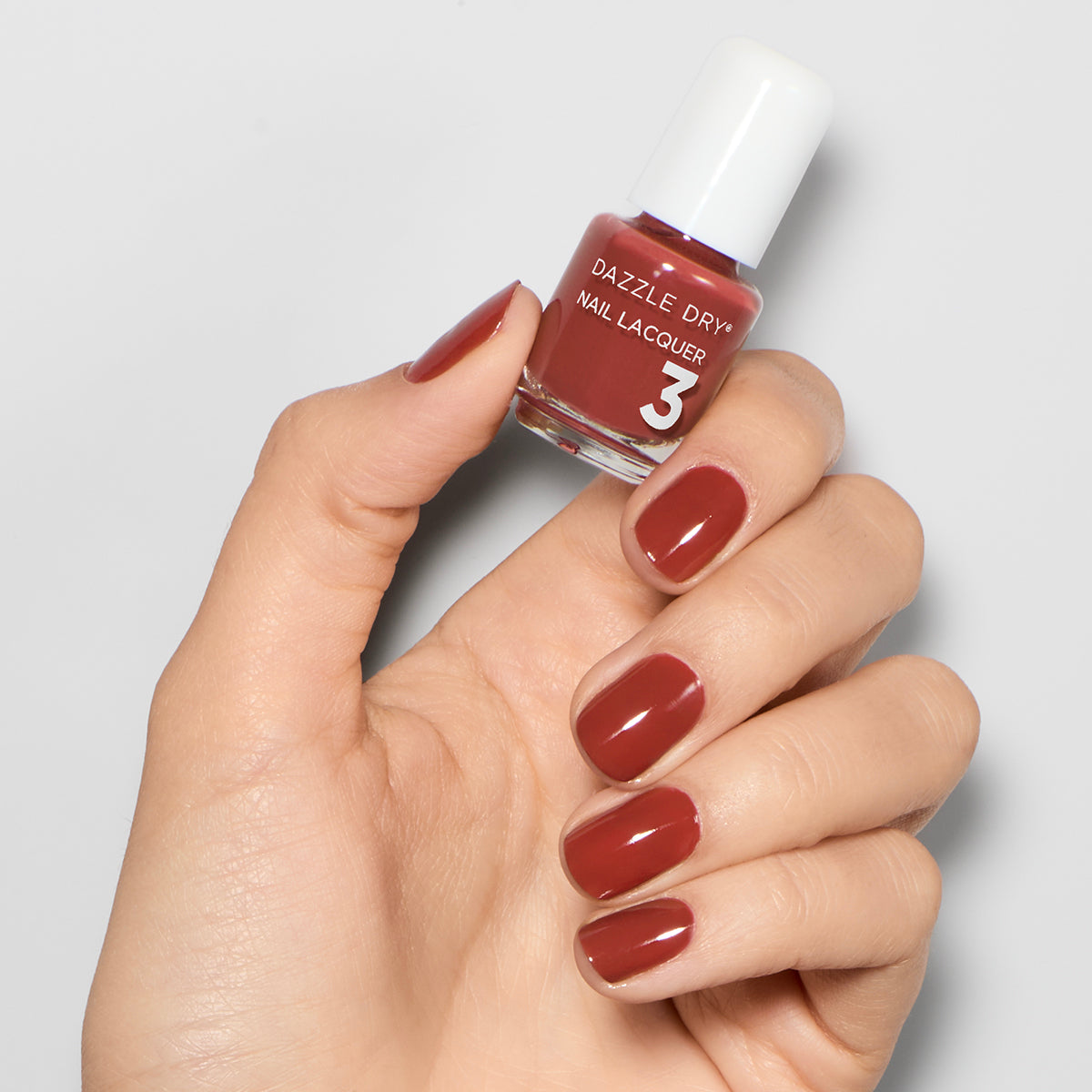 Hand with Cinnamon Spice painted on nails holding mini lacquer bottle