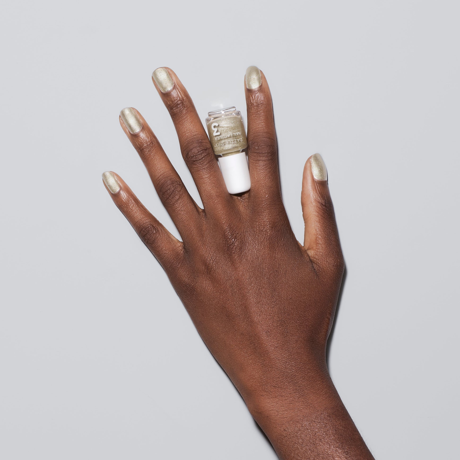 Hand with Illuminate painted on nails holding mini nail lacquer bottle