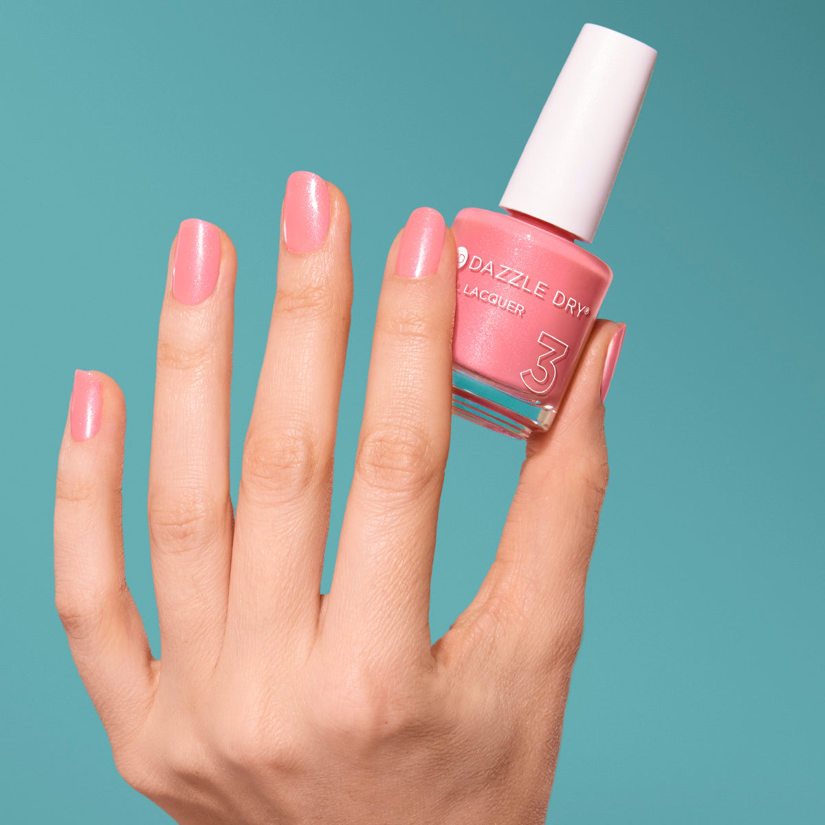 Hand with Cherry Blossom painted on nails holding full size lacquer bottle