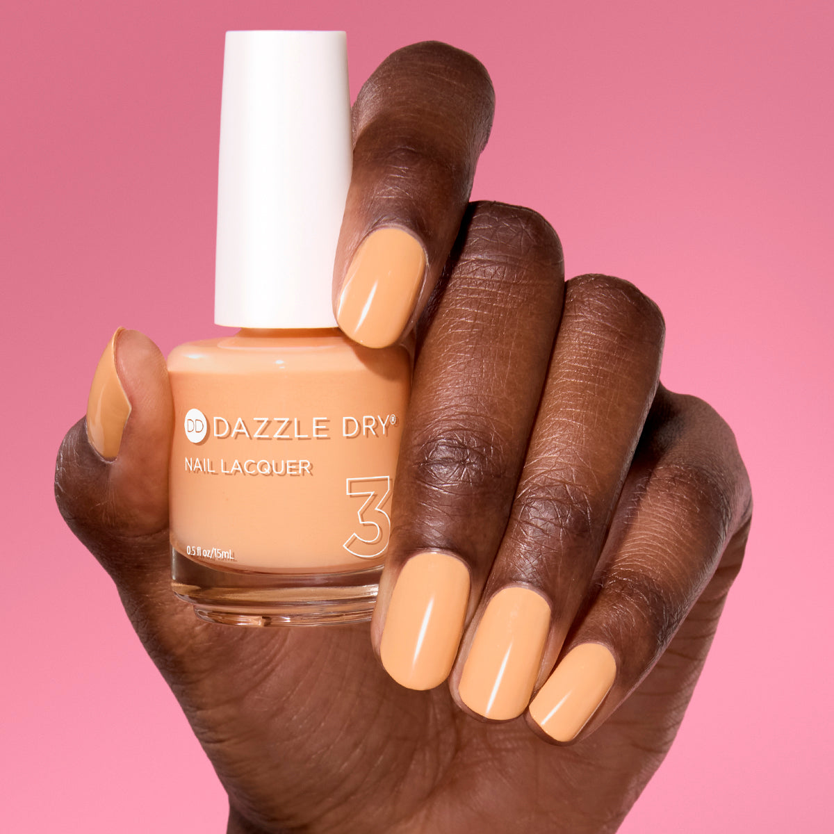 Hand with Creamsicle Sorbet painted on nails holding full size lacquer bottle