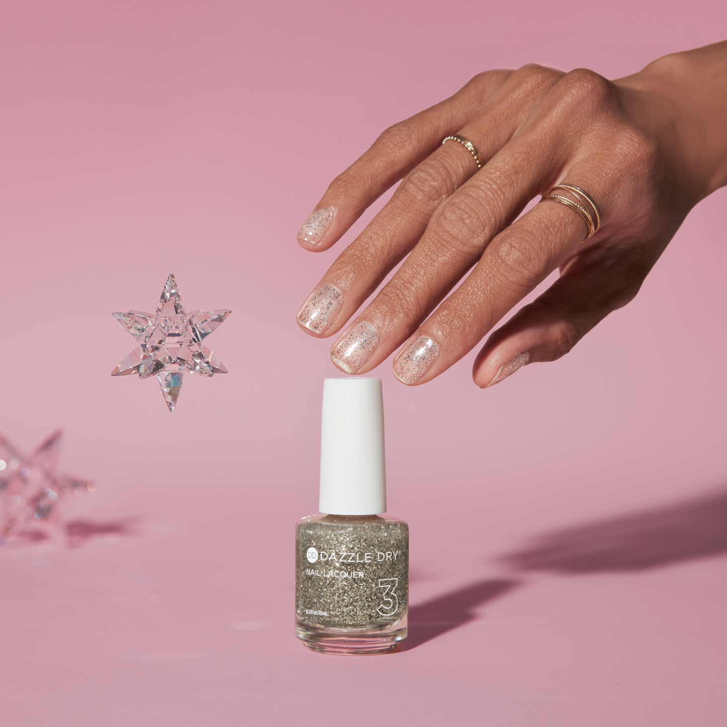 Hand with Shooting Star painted on nails touching nail lacquer bottle